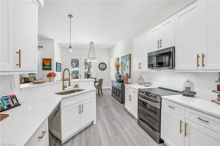 Kitchen featuring white cabinetry, stainless steel appliances, pendant lighting, sink, and backsplash