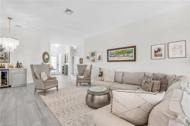 Living room with light hardwood / wood-style flooring, beverage cooler, and a chandelier