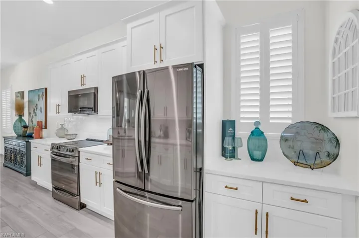 Kitchen with white cabinetry, tasteful backsplash, light hardwood / wood-style flooring, and appliances with stainless steel finishes