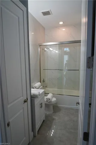 Full bath featuring enclosed tub / shower combo, vanity, and recessed lighting