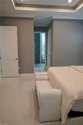 Tiled bedroom featuring crown molding, a tray ceiling, and recessed lighting