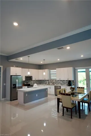 Kitchen with crown molding, white cabinetry, stainless steel appliances, decorative backsplash, and recessed lighting