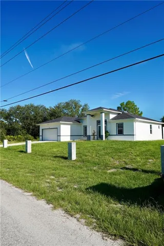 View of front of property with stucco siding, an attached garage, and a front lawn