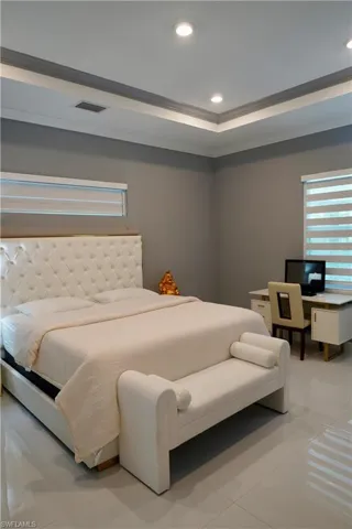 Tiled bedroom featuring recessed lighting, a raised ceiling, crown molding, and an office area