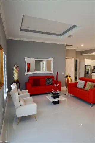 Living room featuring a raised ceiling, crown molding, tile patterned flooring, and recessed lighting