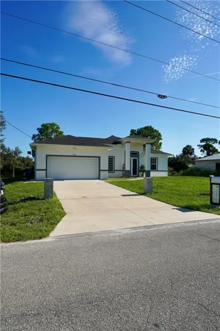 Ranch-style home featuring a front lawn, stucco siding, an attached garage, and concrete driveway