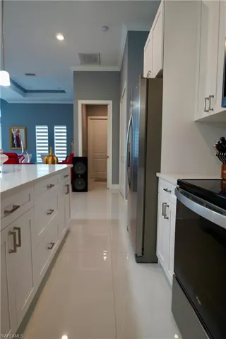 Kitchen featuring black range with electric cooktop, white cabinets, recessed lighting, ornamental molding, and freestanding refrigerator