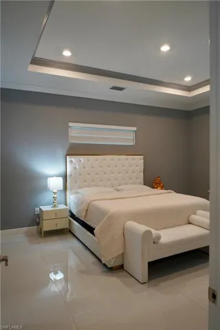 Tiled bedroom featuring a tray ceiling, recessed lighting, and crown molding