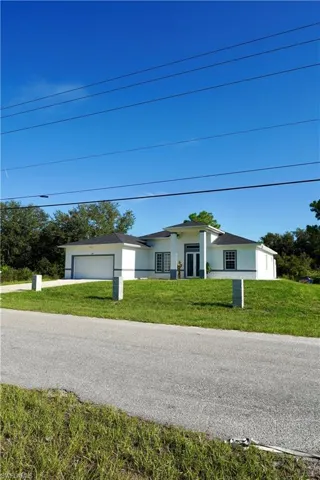 Ranch-style house featuring stucco siding, a front yard, an attached garage, and driveway