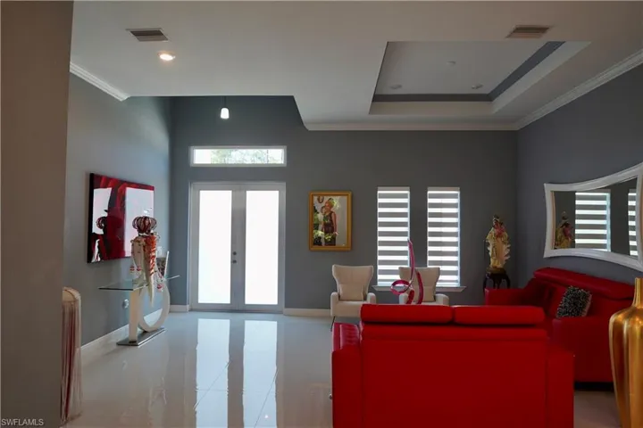 Living area with ornamental molding, french doors, tile patterned floors, and a tray ceiling