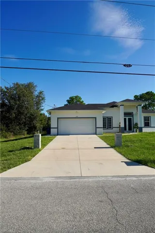 View of front facade with a front yard, an attached garage, stucco siding, and concrete driveway
