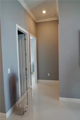 Hallway with light tile patterned floors and ornamental molding