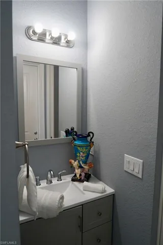 Bathroom featuring a textured wall and vanity