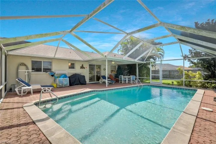 Pool with a patio, area for grilling, fence, and glass enclosure