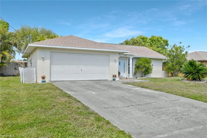 Single story home with a garage, a front lawn, fence, and stucco siding