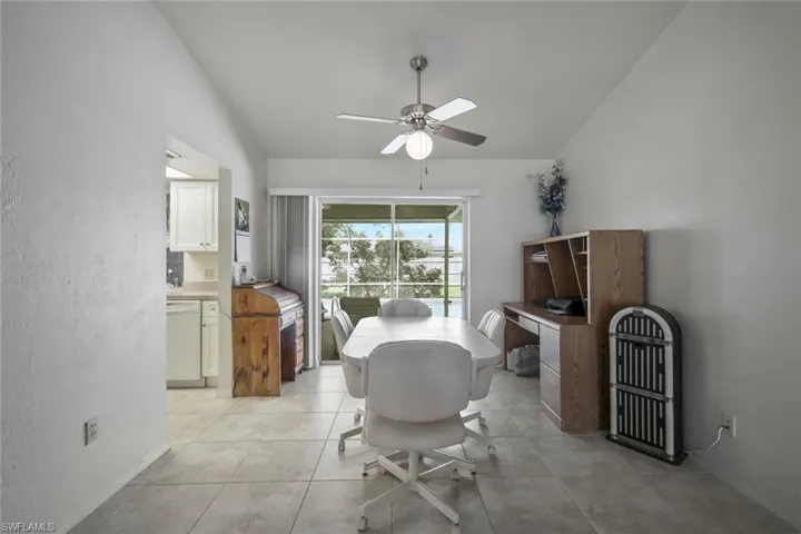 Dining area with vaulted ceiling, light tile patterned flooring, and a ceiling fan