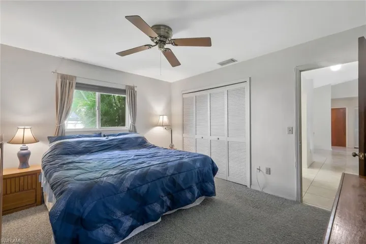 Bedroom featuring light carpet, ceiling fan, visible vents, and a closet