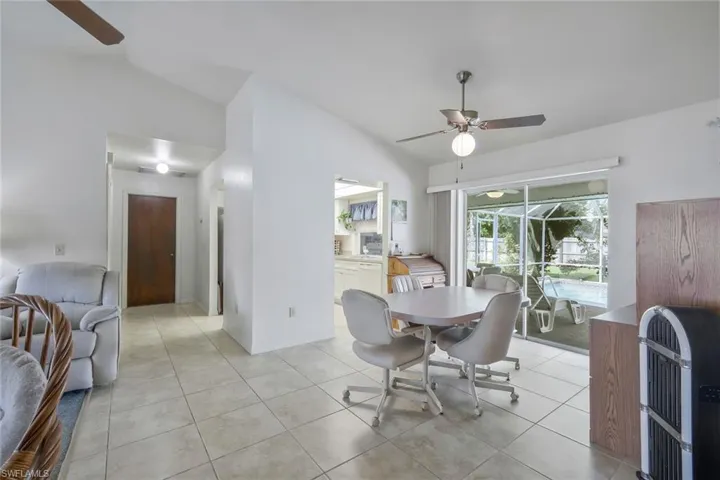 Dining space with heating unit, light tile patterned floors, lofted ceiling, a sunroom, and ceiling fan