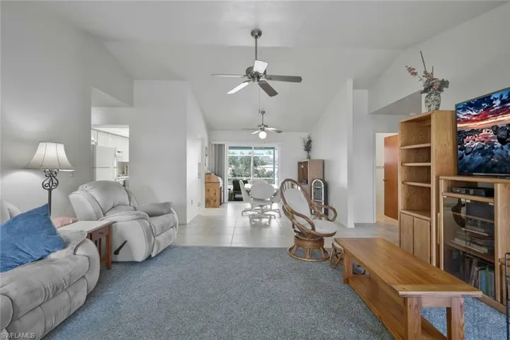 Living area featuring lofted ceiling, light colored carpet, and light tile patterned flooring