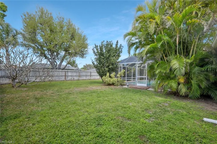 View of yard featuring glass enclosure, a fenced backyard, and a fenced in pool