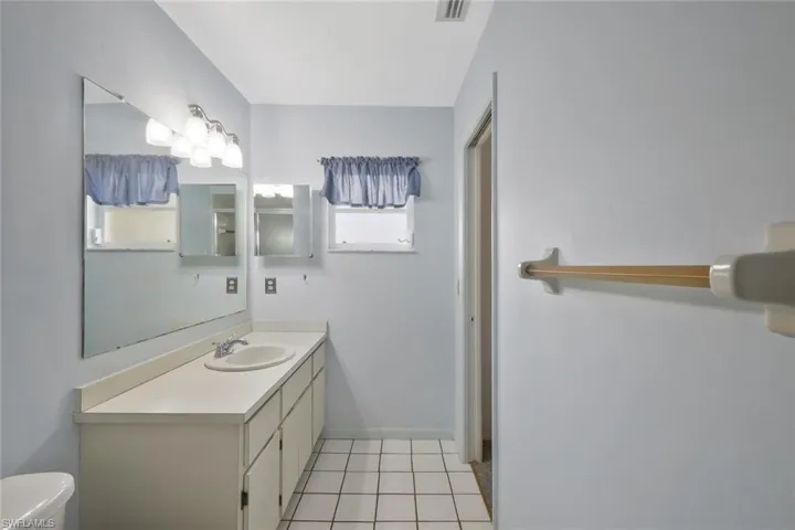 Bathroom with tile patterned flooring, visible vents, vanity, and toilet