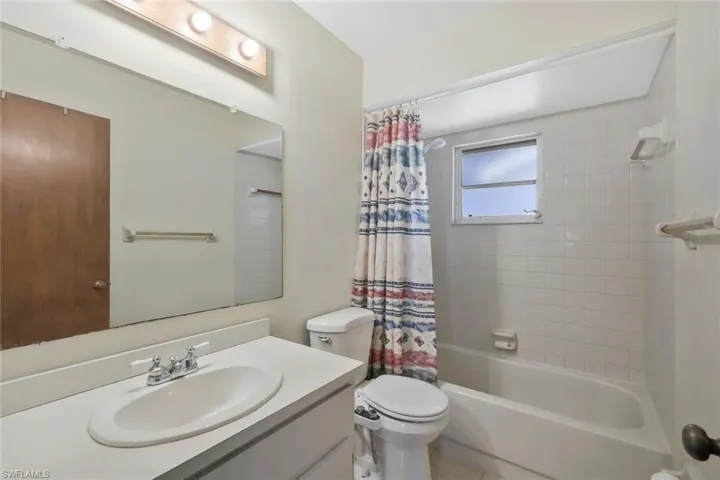 Bathroom featuring vanity, shower / bath combo with shower curtain, and toilet