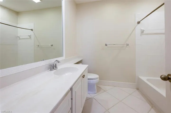 Full bathroom with baseboards, toilet, tile patterned floors, vanity, and shower / washtub combination