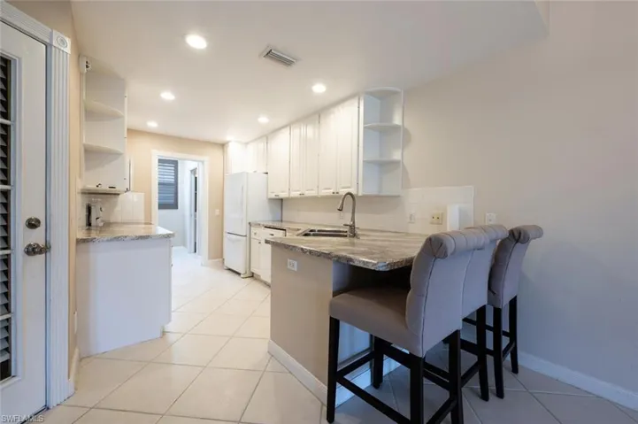 Kitchen with white cabinets, visible vents, open shelves, and a sink