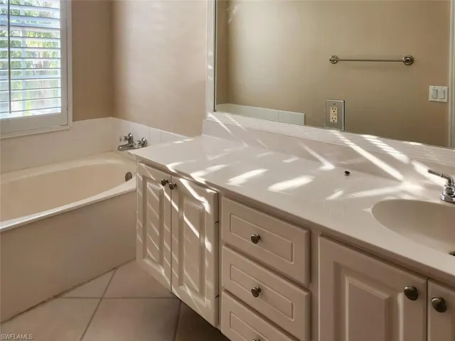 Bathroom featuring a garden tub, tile patterned flooring, and vanity