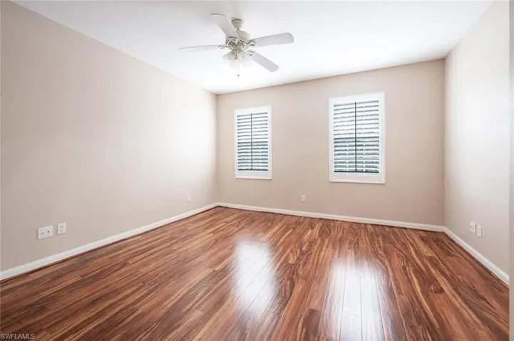 Empty room with wood finished floors, a ceiling fan, and baseboards