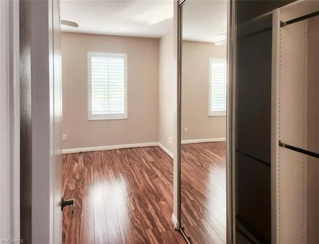 Unfurnished bedroom featuring multiple windows, wood finished floors, and baseboards