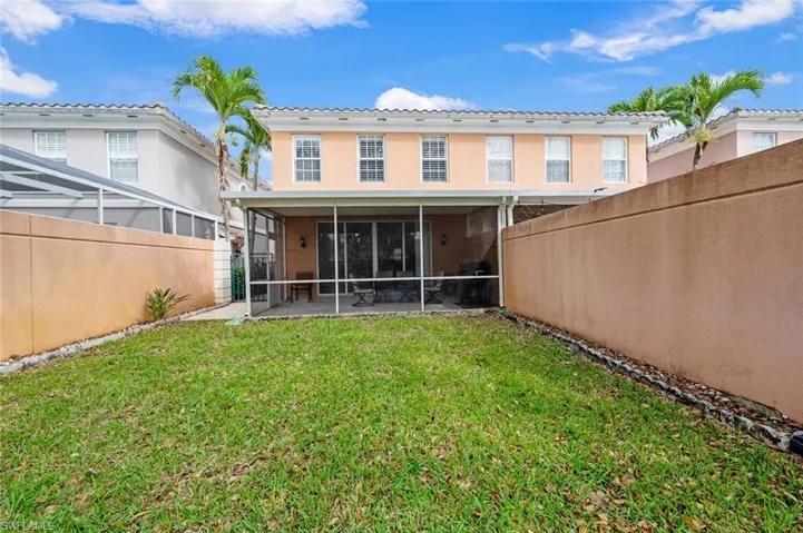 Rear view of house with a sunroom, a fenced backyard, stucco siding, and a yard