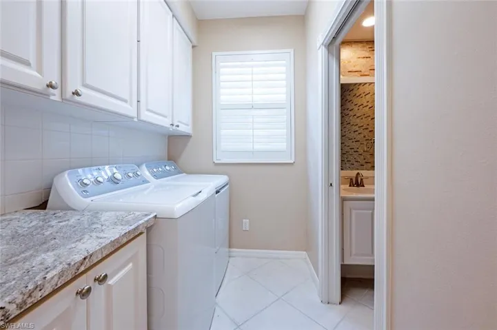 Laundry area featuring cabinet space, baseboards, washer and clothes dryer, and light tile patterned flooring
