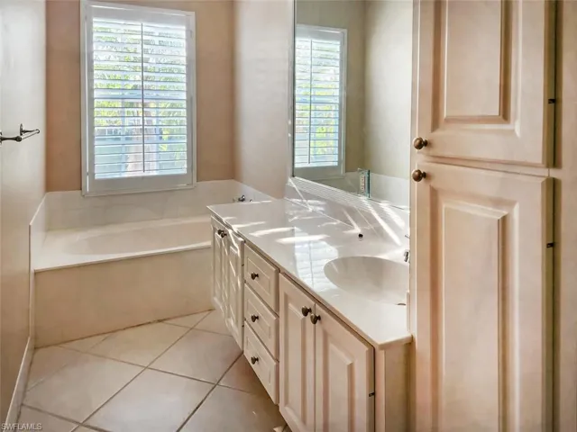 Full bathroom with double vanity, a sink, a bath, and tile patterned floors