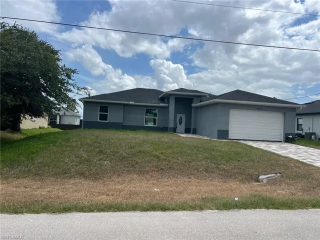 View of front of house with a front yard, a garage, and central AC