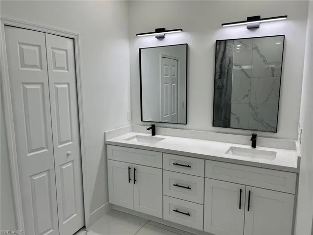 Bathroom with dual vanity, tiled shower, and tile floors