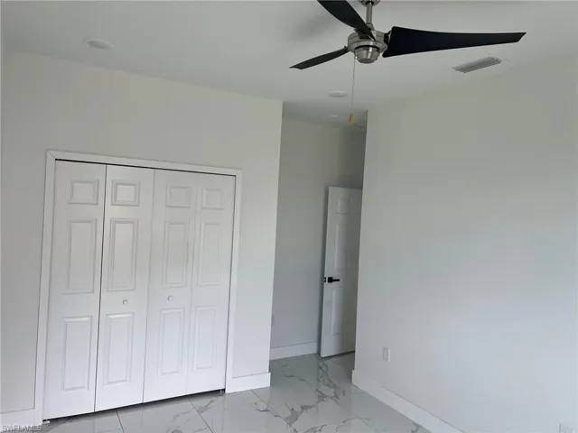 Unfurnished bedroom with ceiling fan, a closet, and light tile floors