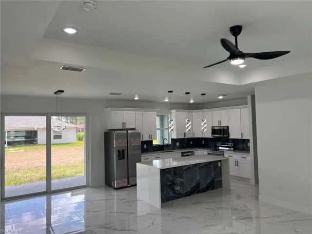 Kitchen with appliances with stainless steel finishes, decorative light fixtures, sink, and backsplash