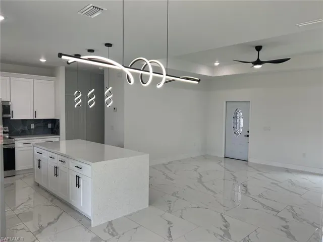 Kitchen featuring light tile flooring, tasteful backsplash, and pendant lighting
