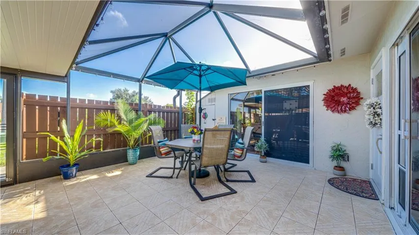 Screened-in patio featuring tile flooring, metal frame enclosure, and a wood-slat privacy fence