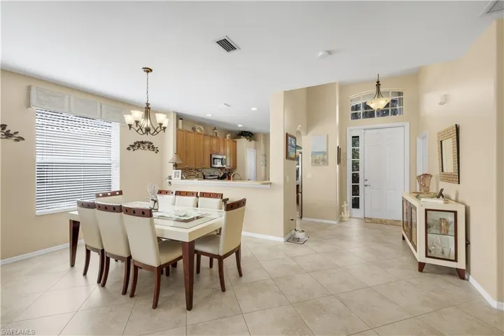 Dining area with light tile patterned floors, recessed lighting, and a chandelier