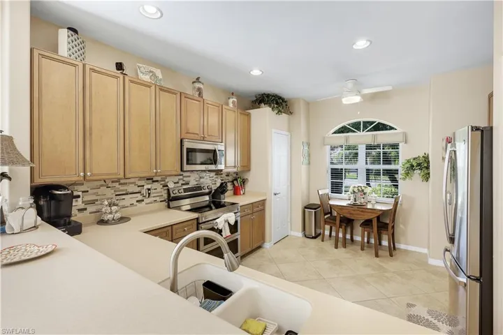 Kitchen featuring stainless steel appliances, light countertops, recessed lighting, a ceiling fan, and backsplash