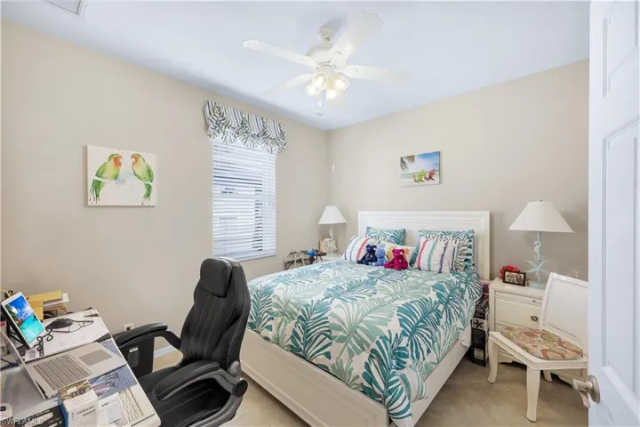 Tiled bedroom featuring ceiling fan and a desk