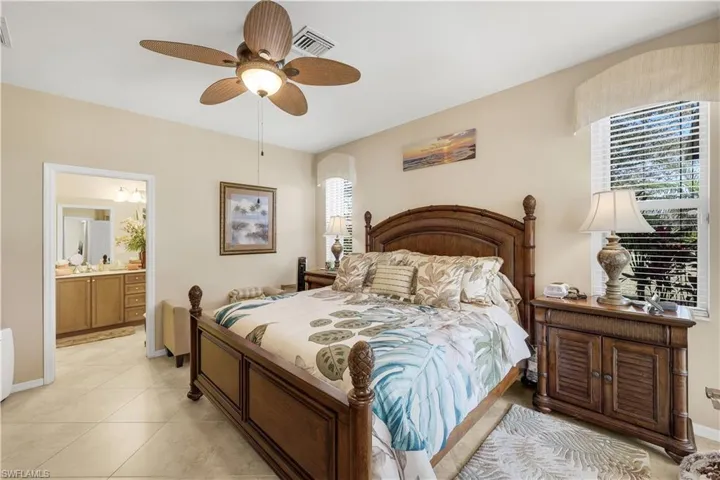 Bedroom featuring ceiling fan, ensuite bathroom, and light tile patterned floors