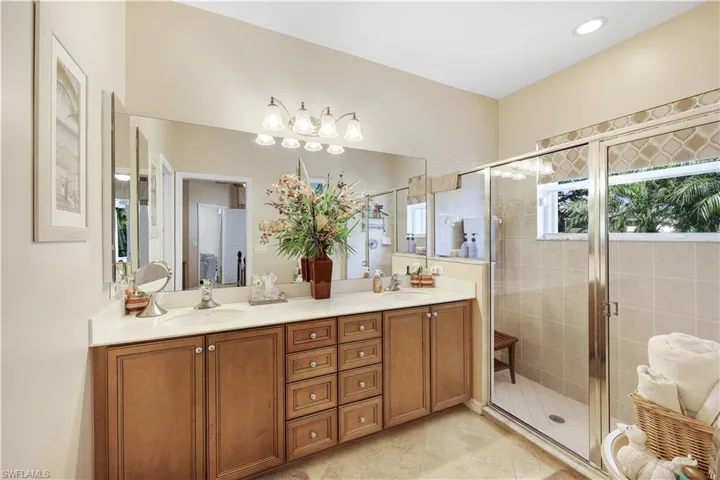 Full bathroom featuring double vanity, a shower stall, and light tile patterned floors