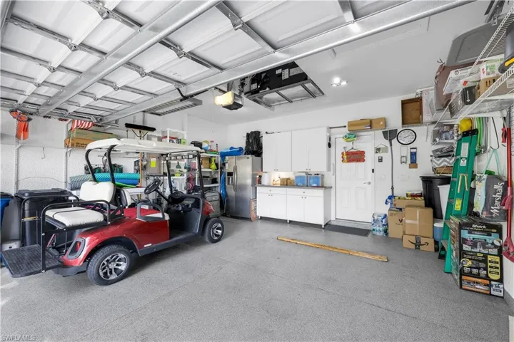 Garage with stainless steel fridge with ice dispenser and a garage door opener