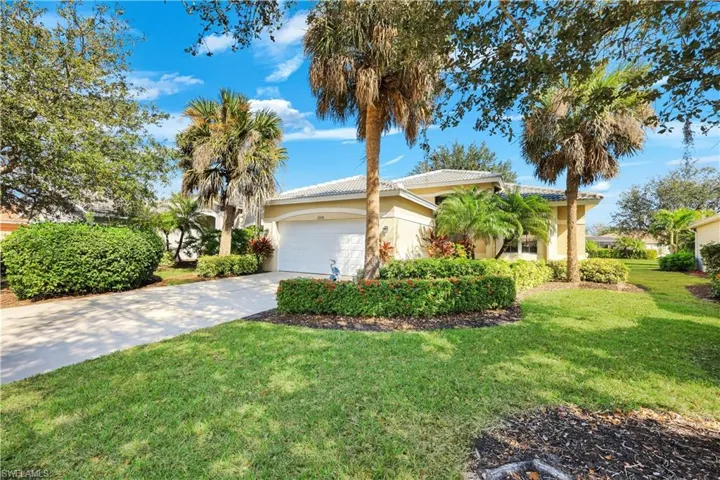View of front of house featuring concrete driveway, a front lawn, a tiled roof, a garage, and stucco siding