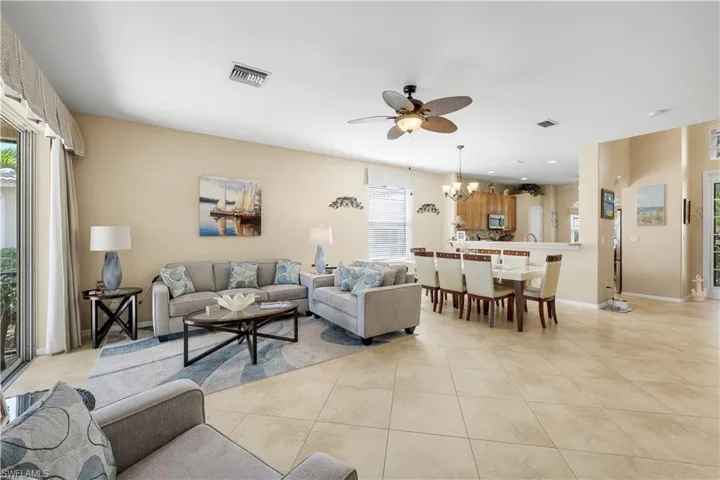 Living area with light tile patterned flooring, ceiling fan, a chandelier, and recessed lighting