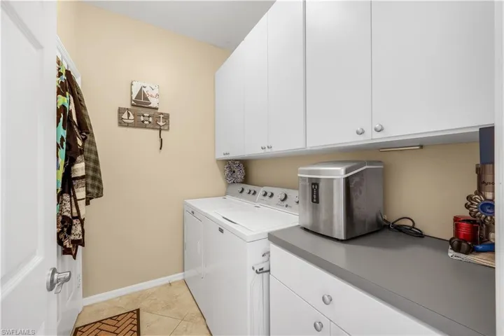 Laundry area with cabinet space, separate washer and dryer, and light tile patterned floors