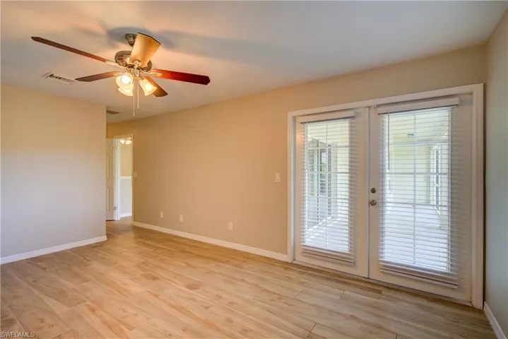 Empty room featuring french doors, light wood-style flooring, and a ceiling fan